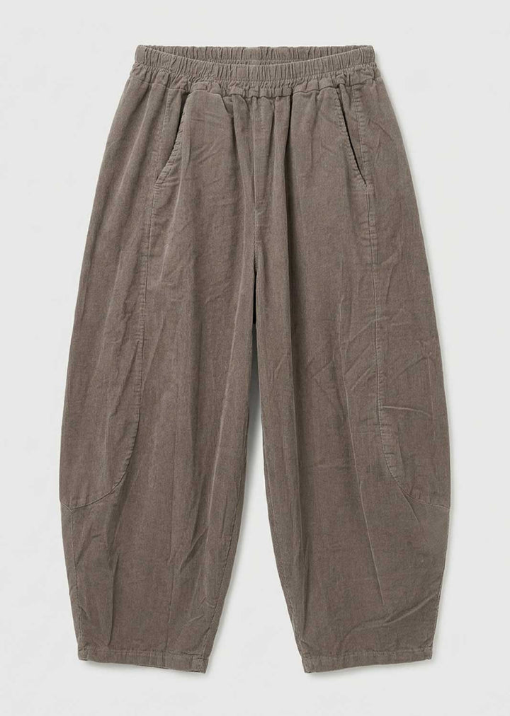 A pair of loose, relaxed-fit needlecord barrel leg pants in a muted taupe fabric, featuring an elastic waistband and side pockets, laid flat against a light gray background.