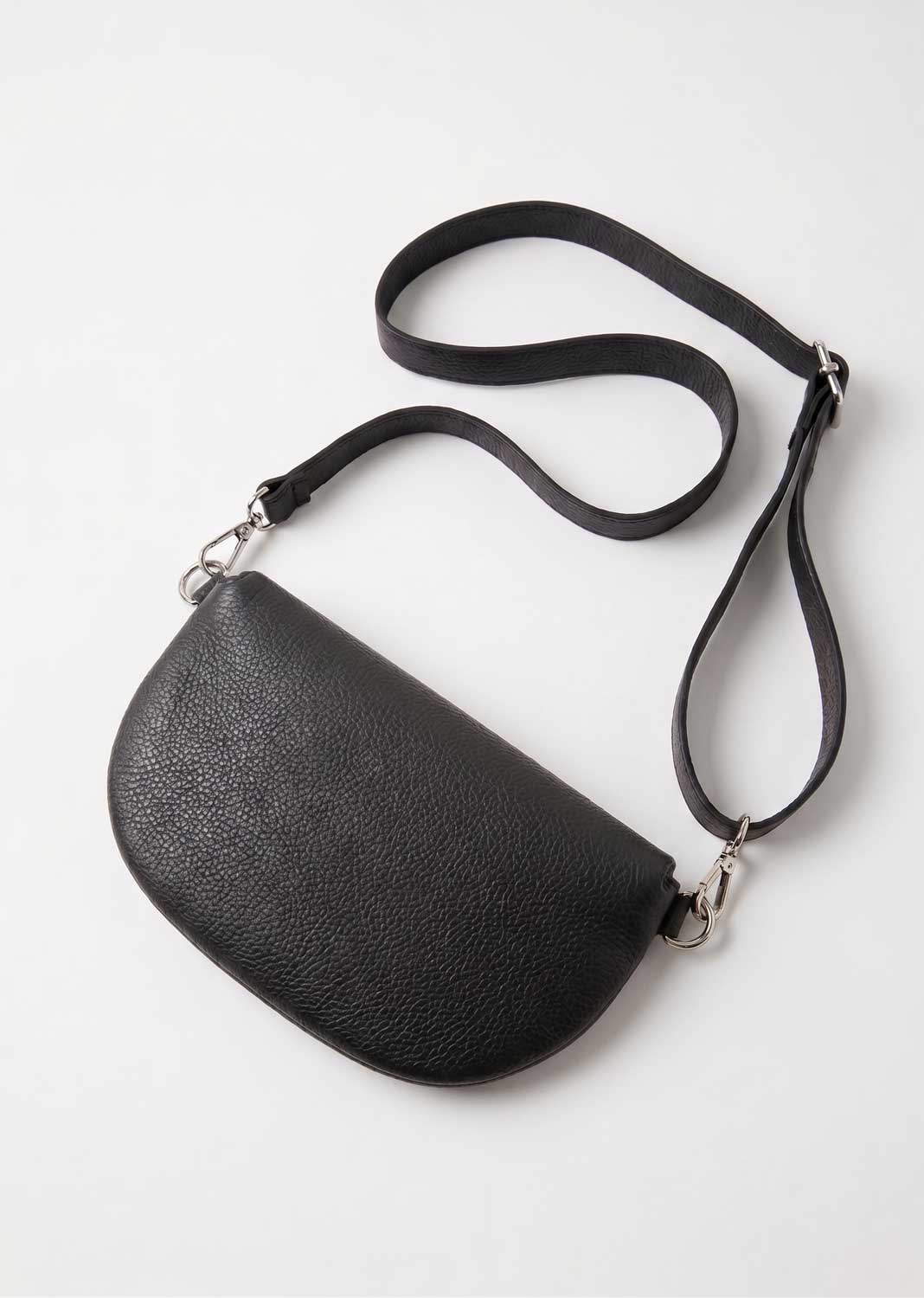 A black pebbled leather crescent-shaped crossbody bag with a long adjustable shoulder strap, shown on a clean white background.