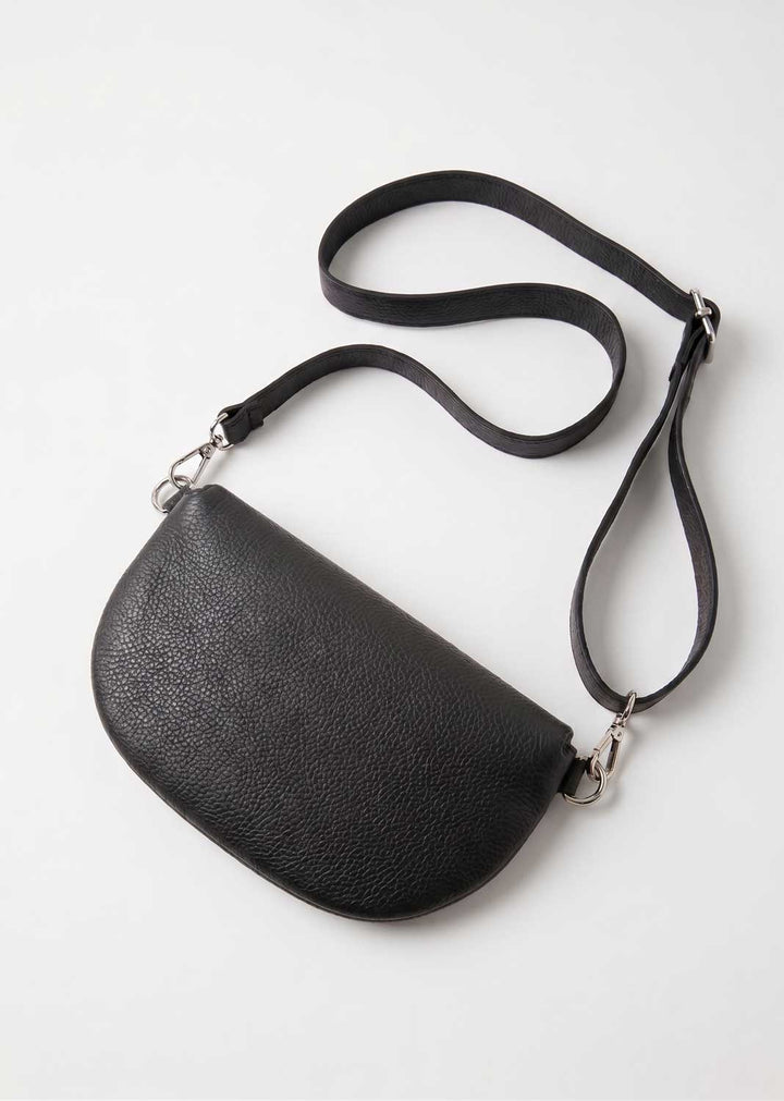 A black pebbled leather crescent-shaped crossbody bag with a long adjustable shoulder strap, shown on a clean white background.