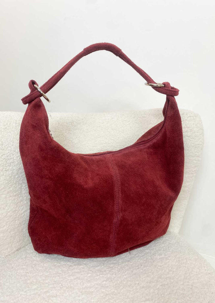 Burgundy suede handbag on a white surface