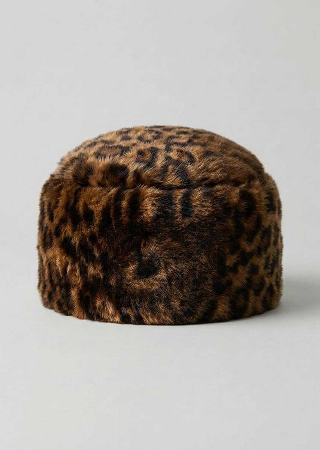 A brown and black leopard-print faux fur hat, photographed against a neutral light gray background.