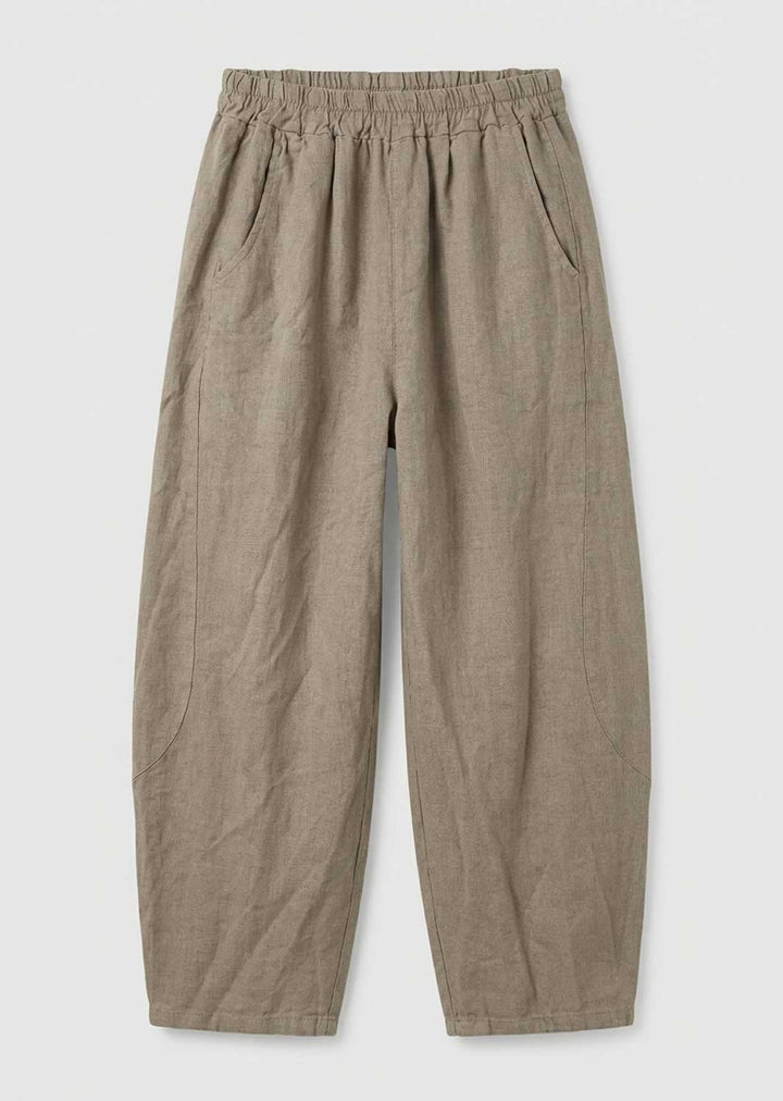 A pair of loose, wide-leg trousers in a textured taupe-beige fabric, featuring an elastic waistband and side pockets, shown flat on a light gray background.