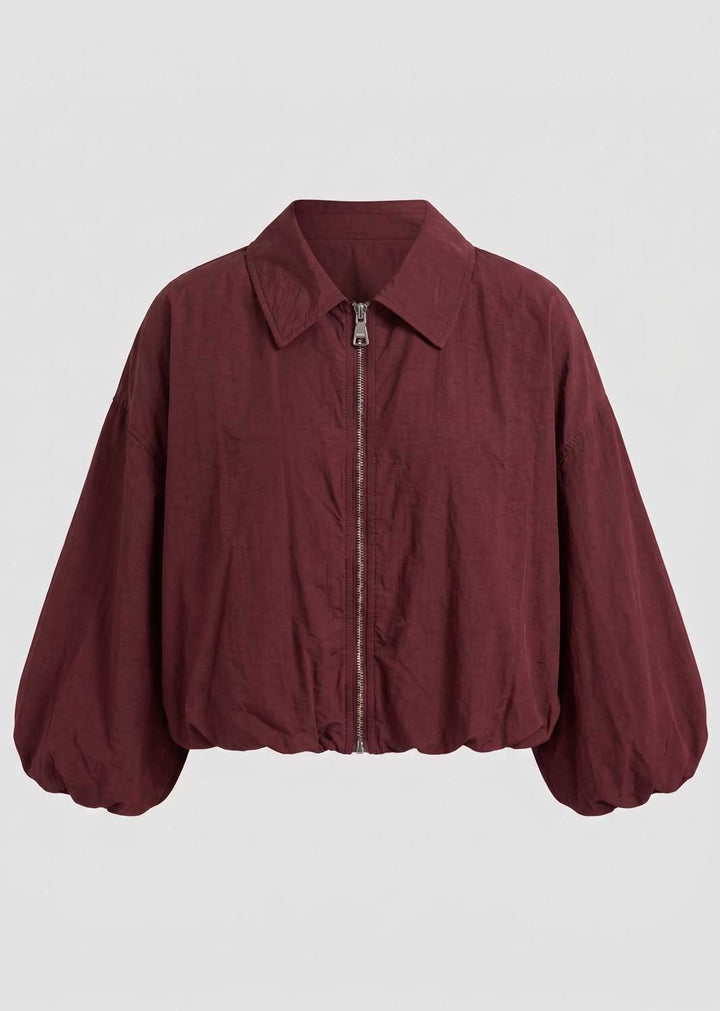 A cropped, long-sleeve windbreaker jacket in a deep burgundy
