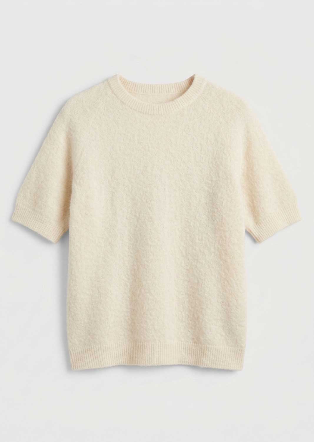 A short-sleeve crewneck knit sweater in a soft cream or off-white color, displayed flat against a light gray background.
