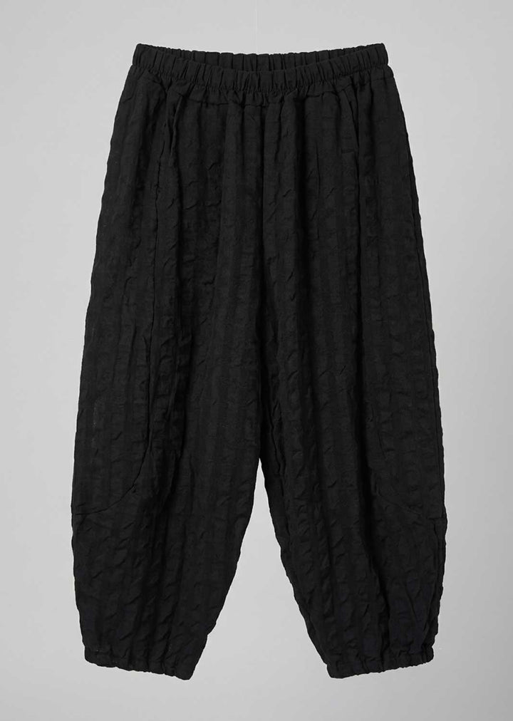 Black textured crinkled pants with an elastic waistband and tapered legs, shown flat against a light gray background.