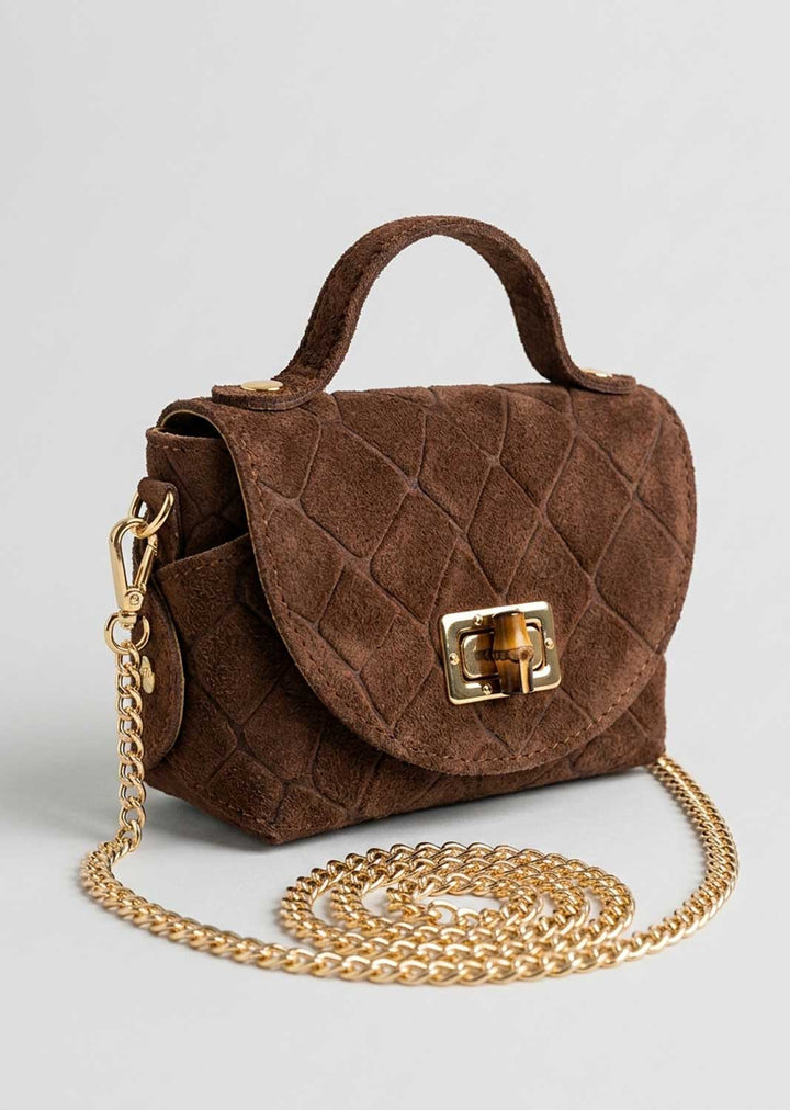 A brown croc suede handbag with a top handle, gold-tone turn-lock clasp, and a long gold chain strap, displayed on a light gray background.