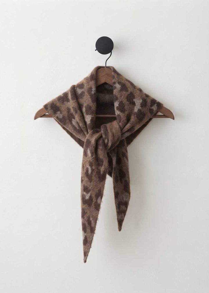A brown and beige leopard-print scarf tied in a knot on a wooden hanger against a plain off-white wall.