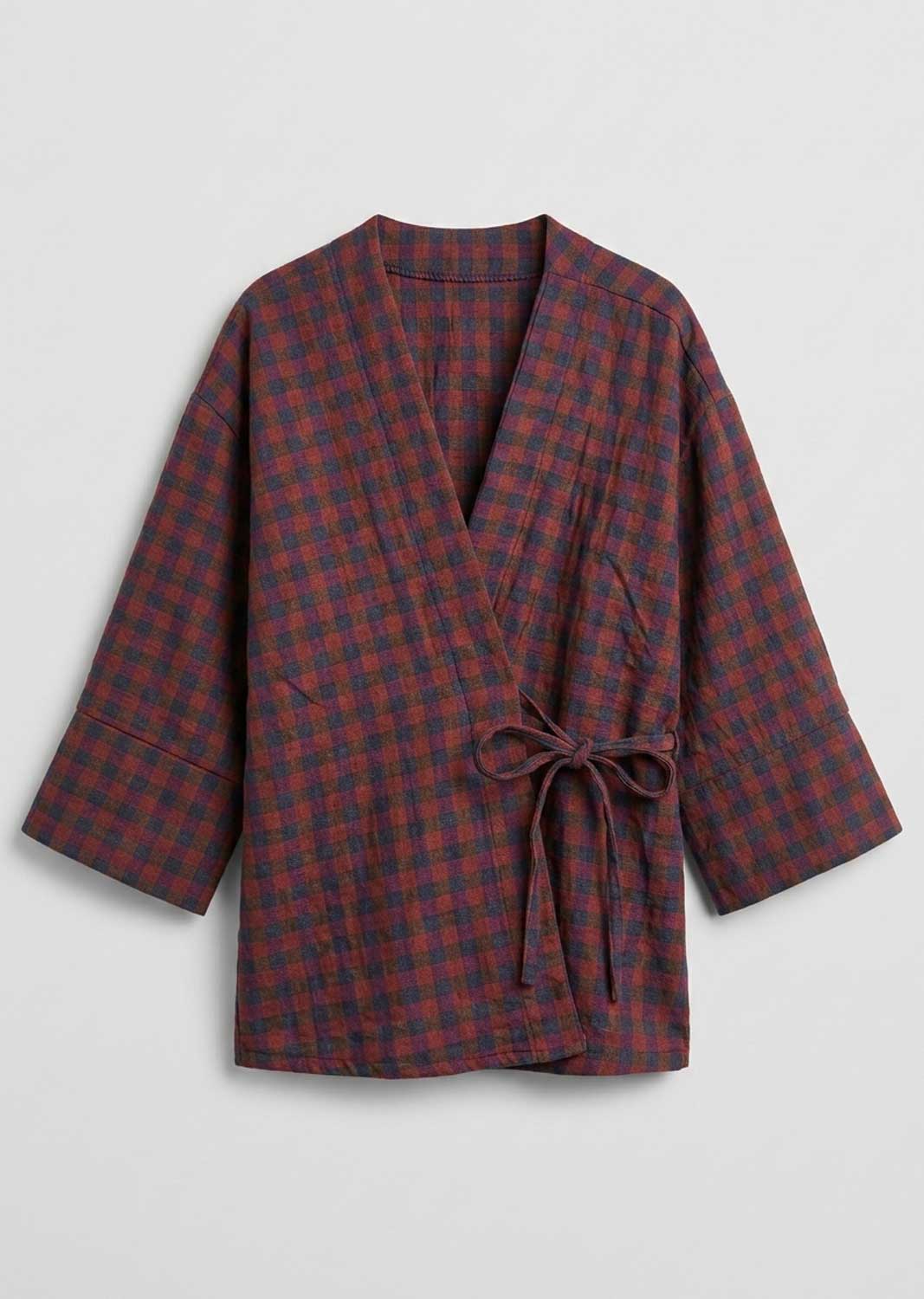 A long-sleeved wrap robe with a red and dark blue plaid pattern, featuring a tie belt at the waist, displayed against a light gray background. 