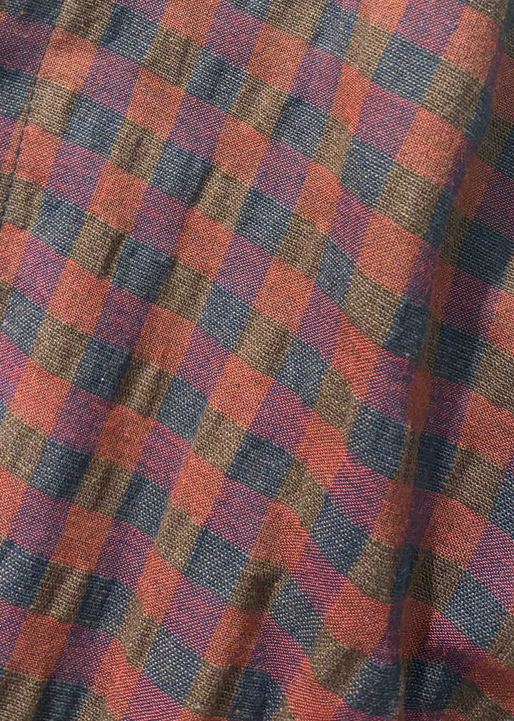 A close-up of a textured plaid fabric with a diagonal checkered pattern in burgundy rust orange, navy blue, and brown.