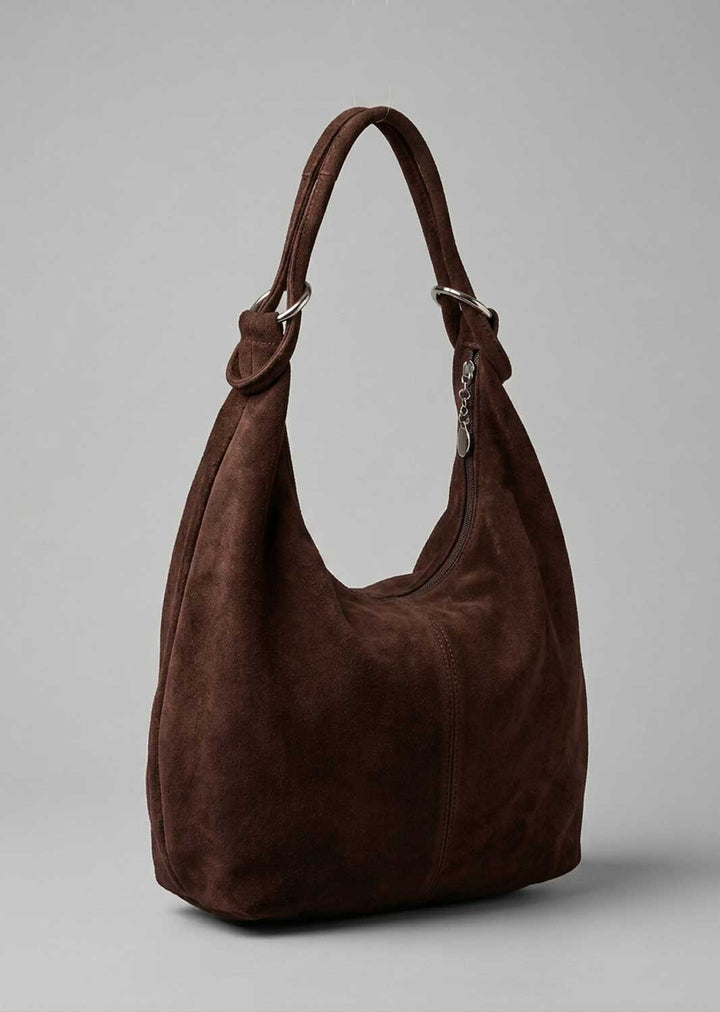 A dark brown suede hobo shoulder bag with silver-tone hardware, shown on a neutral gray background.