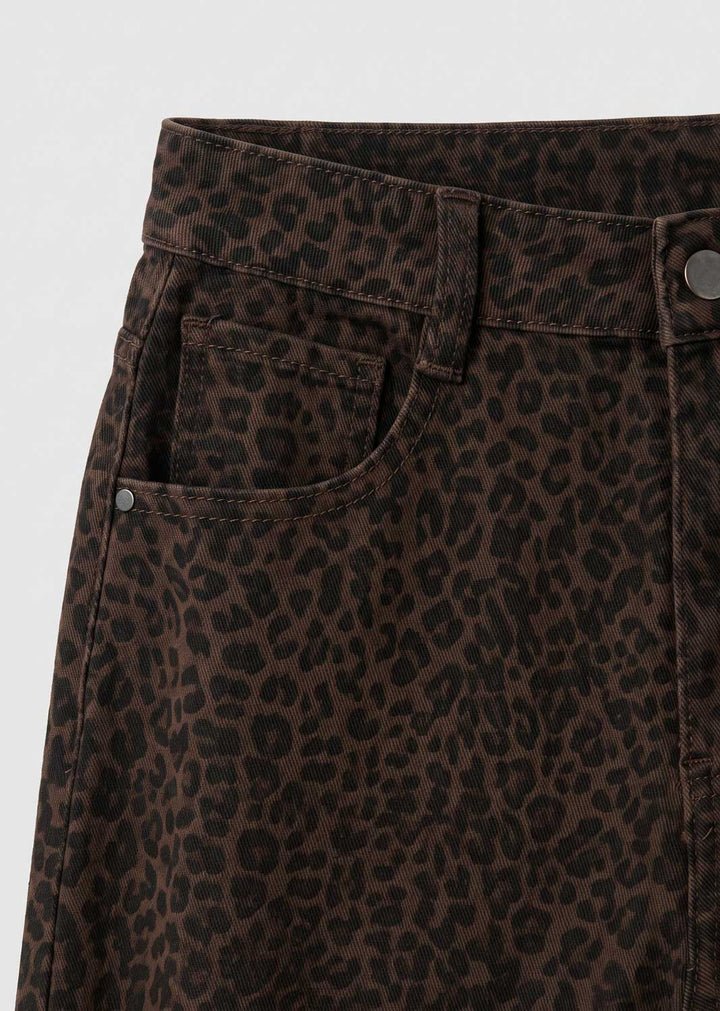 Close-up of dark brown leopard-print jeans showing the waistband, belt loops, front pocket, and metal rivets against a light gray background.