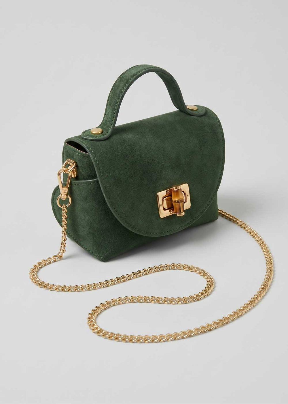 A dark green suede top-handle handbag with a gold-tone turn-lock clasp and a gold chain shoulder strap, displayed on a light gray background.