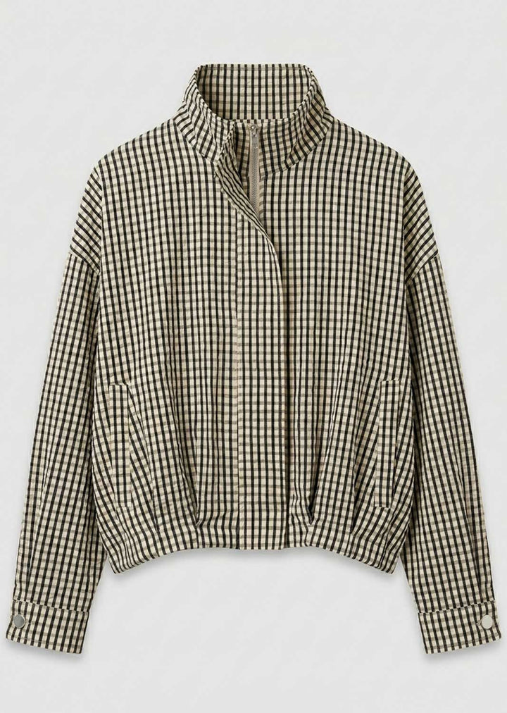 A cropped long-sleeve jacket with a high stand-up collar and an asymmetrical zipper closure, featuring a black and beige gingham check pattern, shown against a plain light gray background.